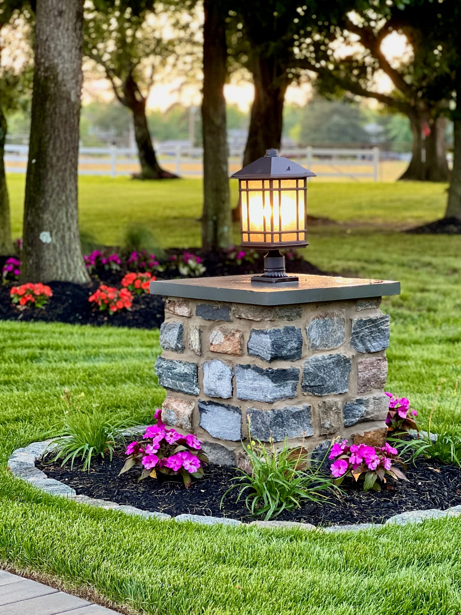 Single stone pillar with lit craftsman lantern at dusk